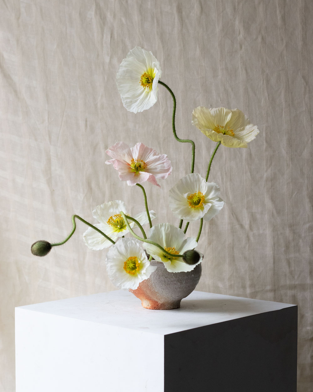 A romantic but playful centrepiece of delightful, delicate looking poppies in pastel tones.  By Mora, a sustainable, season-led event florist based in Hackney, East London.