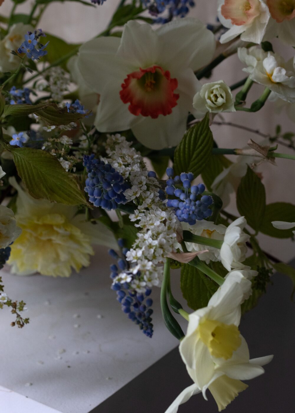 Spring floral table arrangement featuring daffodils, muscari, spirea and forget me nots by Mora Floral Studio in Hackney, East London